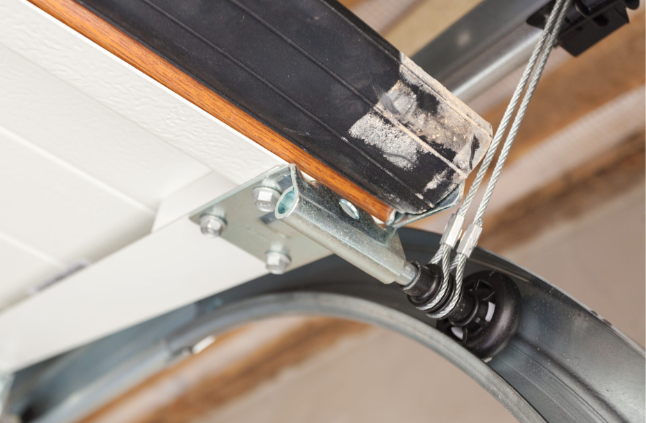 a close up photo of a garage door roller, rubber sealant and cable