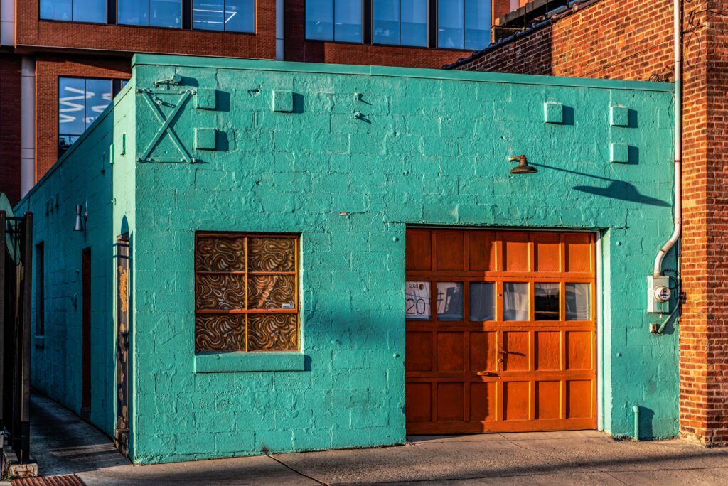 green box building with a small brown wood garage door